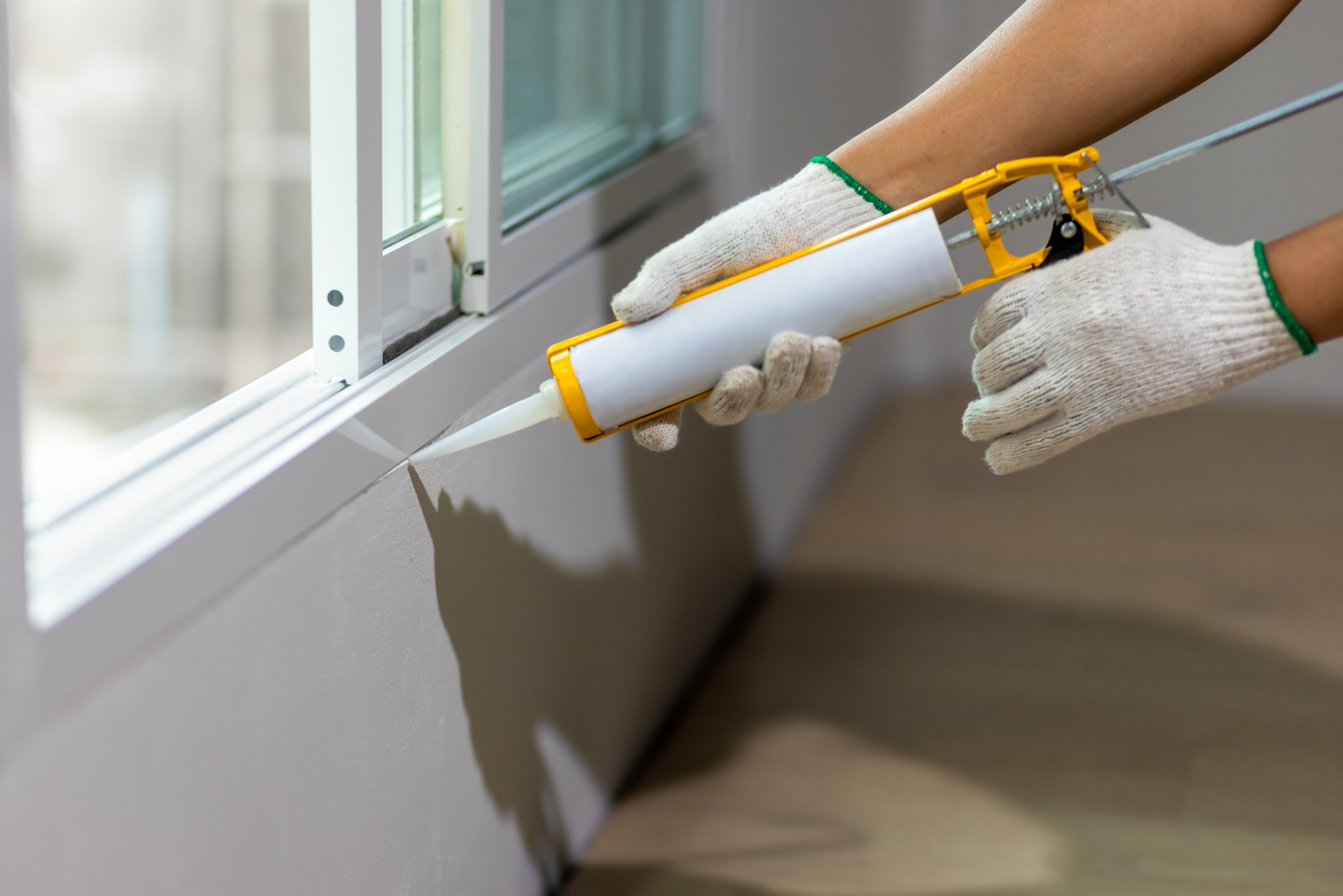 Construction worker using silicone sealant caulk the outside win