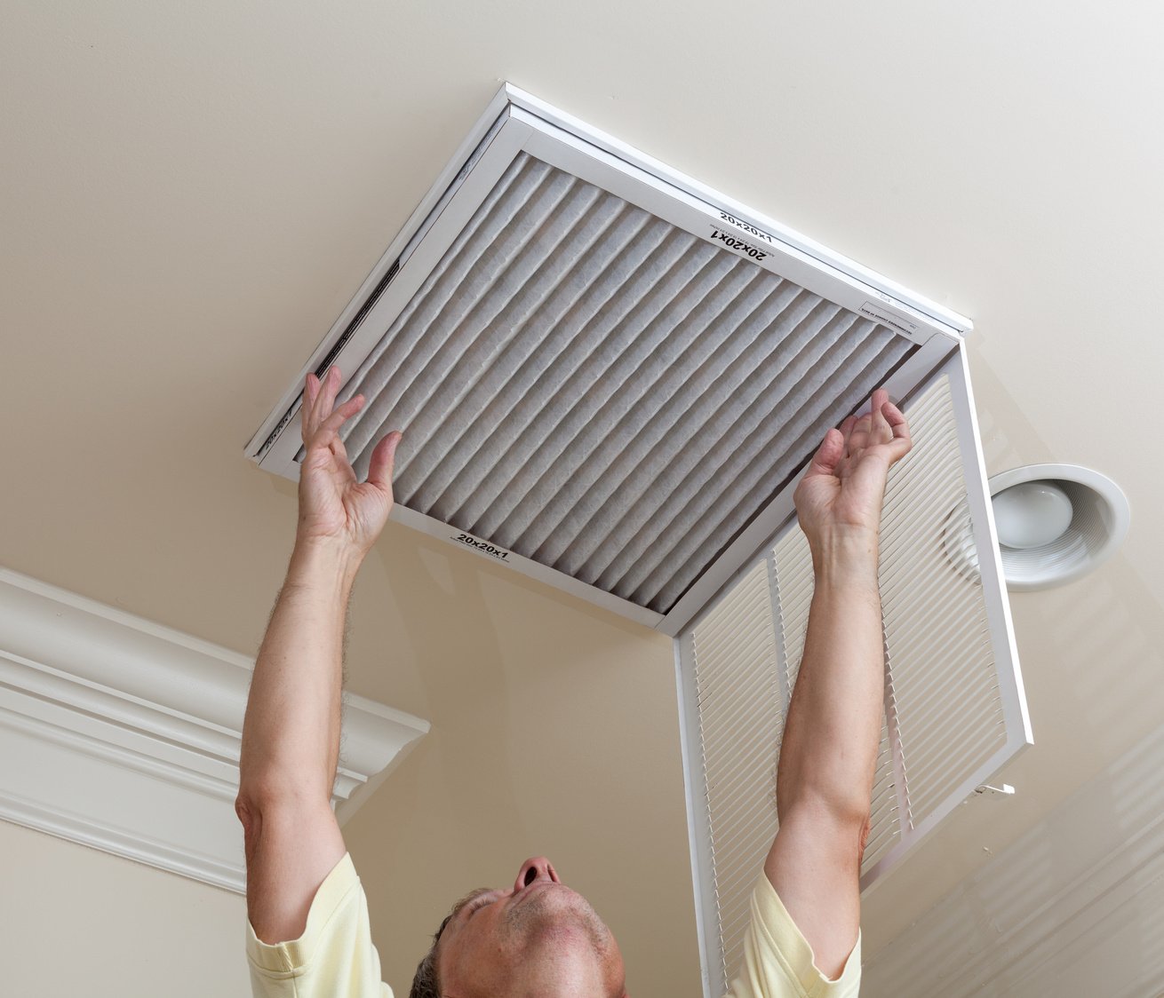 Senior Man Opening Air Conditioning Filter in Ceiling